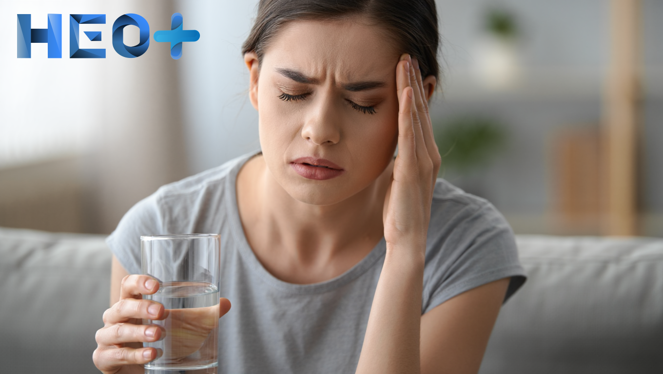 Девушка сидит на диване и держится за голову