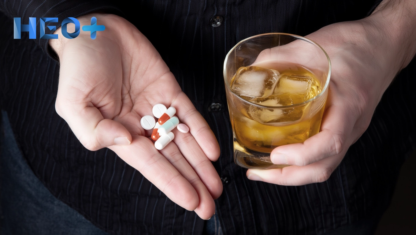 Мужчина с таблетками и стаканом алкоголя в руках